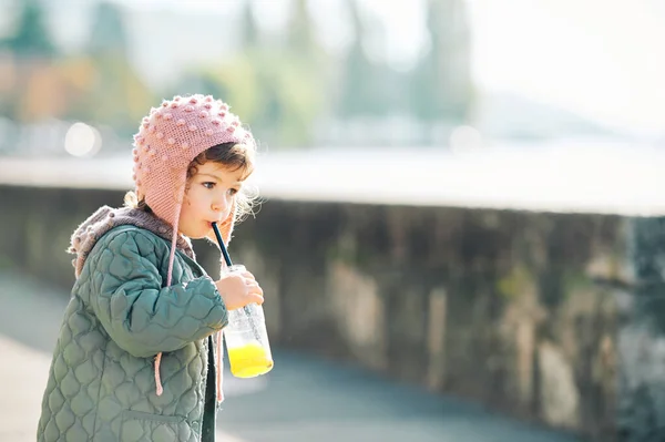 산책을 하면서 오렌지 주스를 마시는 귀여운 소녀의 — 스톡 사진