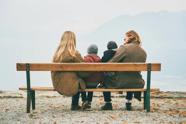 一家人坐在长椅上 享受着湖畔的秋日 寒冷的天气 后视镜 — 图库照片