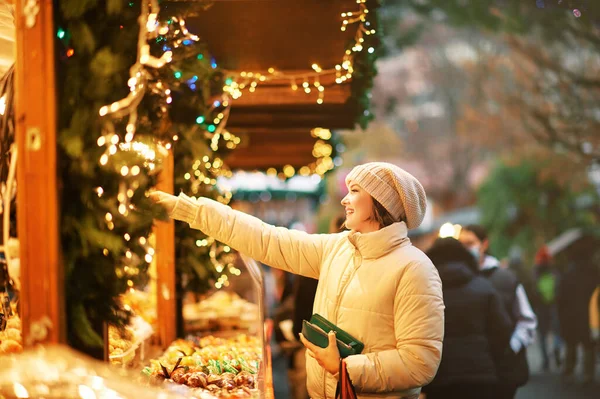 クリスマスマーケットでお菓子を買う若い女性の屋外肖像画 — ストック写真