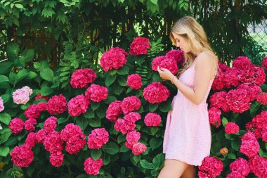 Yazlık bahçede ortanca çiçekleriyle poz veren güzel bir kadının açık hava portresi.