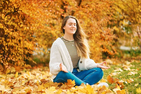 나뭇잎을 배경으로 땅바닥에 밖에서 묵상하고 귀여운 소녀의 — 스톡 사진