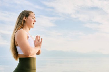Güzel ruhani kadın gölün kenarında meditasyon yapıyor, namaste hareketi.