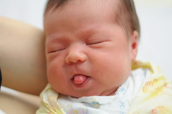 Yeni doğan bebek dili gösterir.