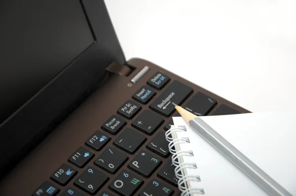 Cuaderno con lápiz en el teclado marrón portátil — Foto de Stock