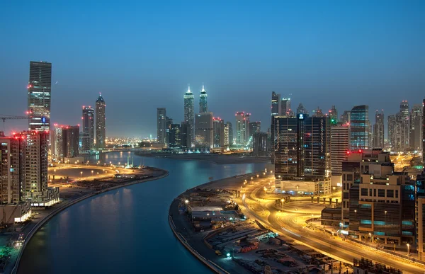 Business Bay Area em Dubai durante Blue Hour ao longo do rio e edifícios altos com uma lua crescente vista do lado esquerdo.Tomado em Dubai, Emirados Árabes Unidos — Fotografia de Stock