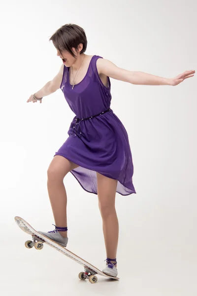 Девушка в платье на скейтборде — стоковое фото