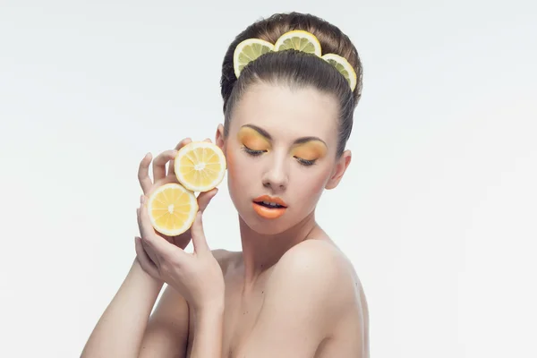 Ung kvinna med apelsiner och makeup — Stockfoto
