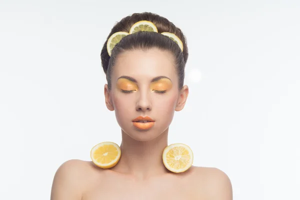 Молодая женщина с апельсинами и макияжем — стоковое фото