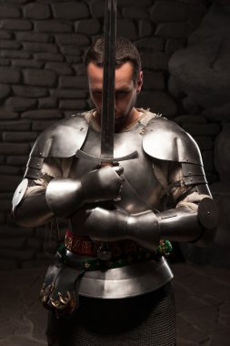 Medieval knight kneeling with sword clipart