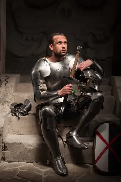 Medieval knight sitting on the steps of ancient temple — Stock Photo, Image