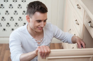Young man assembling furniture clipart