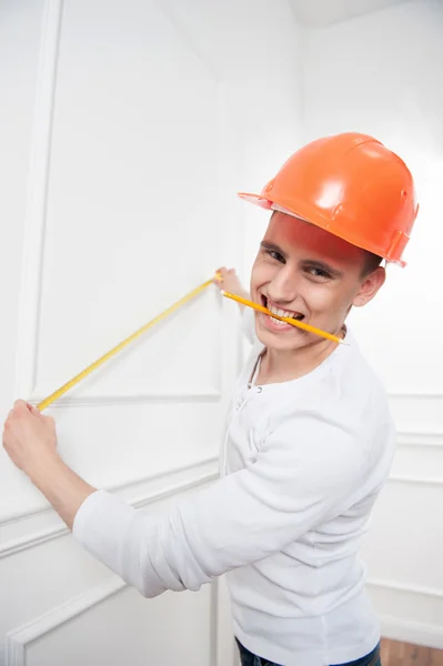 Young handsome worker in helmet with measuring tape — Stock Photo, Image