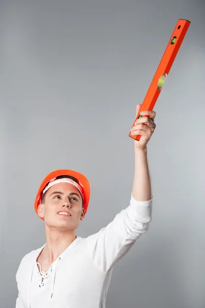 Worker in helmet showing something with spirit level — Stock Photo, Image