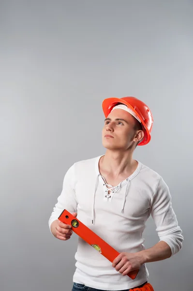 Worker in helmet holding spirit level — Stock Photo, Image