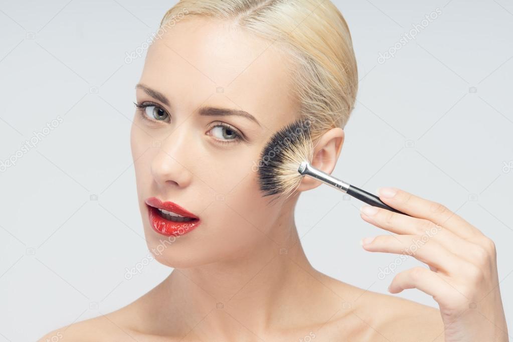 Beautiful Young Woman Applying Makeup with Brush