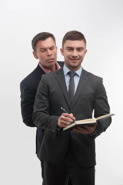 Employee smiling and writing in notebook — Stock Photo, Image