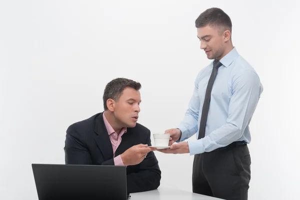 Assistent brengt koffiekopje aan senior manager — Stockfoto