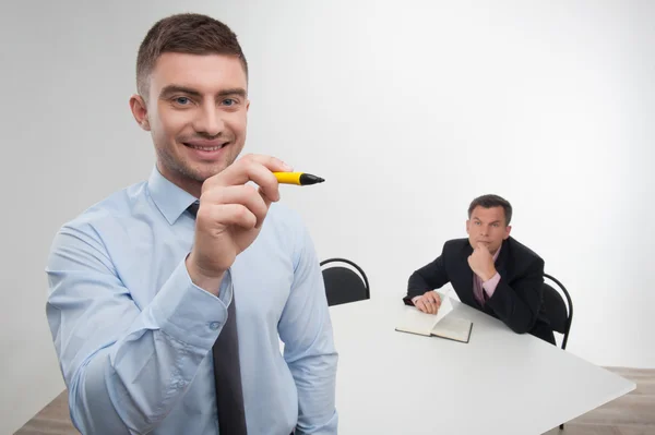 Geschäftsmann zeichnet etwas in die Luft, sein aufmerksamer Kollege mit Notizbuch — Stockfoto