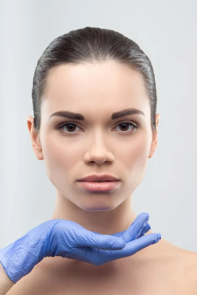 Kosmetikerin in Gummihandschuhen berührt Gesicht der jungen schönen wom — Stockfoto