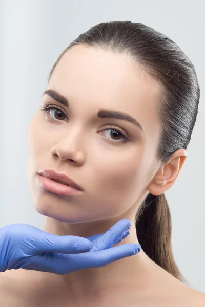 Beautician in rubber gloves touching face of young beautiful wom — Stock Photo, Image