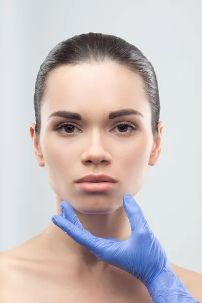 Beautician in rubber gloves touching face of young beautiful wom — Stock Photo, Image