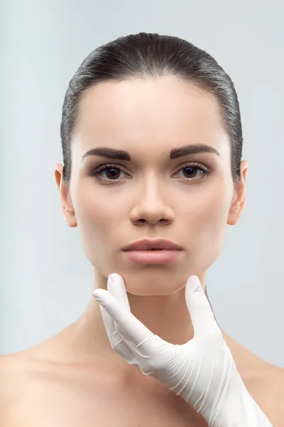 Beautician in rubber gloves touching face of young beautiful wom — Stock Photo, Image