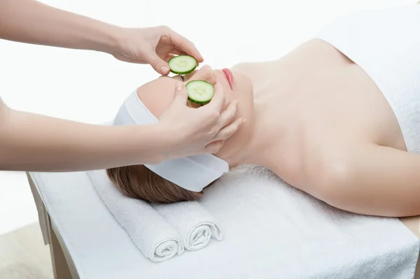 Beautiful young woman receiving facial mask of cucumber in beaut — Stock Photo, Image