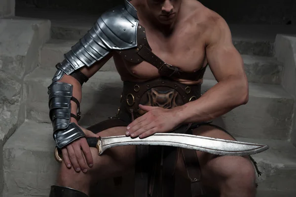 Gladiator in Rüstung sitzt auf den Stufen des antiken Tempels und sieht ein — Stockfoto