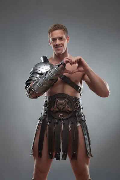 Gladiator in pantser hart teken tonen over grijze achtergrond — Stockfoto