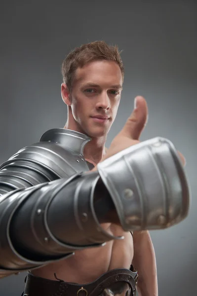 Gladiator in Rüstung zeigt auf etwas vor grauem Hintergrund — Stockfoto