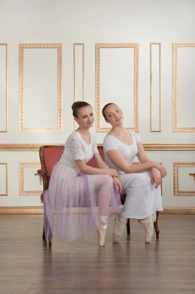 Two young beautiful ballet dancers sitting on sofa in classical — Stock Photo, Image