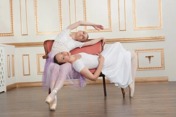 Two young beautiful ballet dancers sitting on sofa in classical — Stock Photo, Image