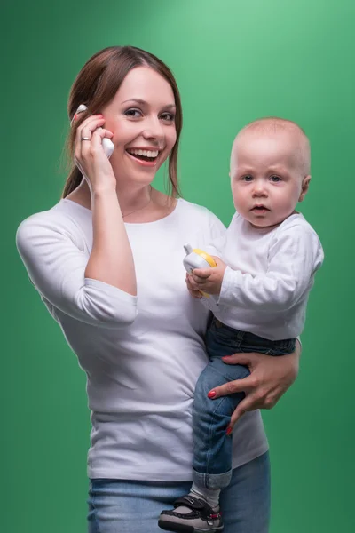 Madre sosteniendo hijo pequeño con teléfono de juguete — Foto de Stock