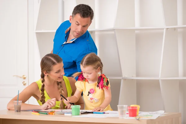 Schöne glückliche Familie zeichnet und malt zu Hause zusammen — Stockfoto