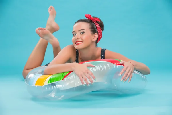 Beautiful girl with pretty smile in pinup style lying on inflata — Stock Photo, Image