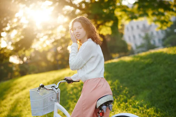 Una joven montando una bicicleta a la luz del sol en el parque — Foto de Stock