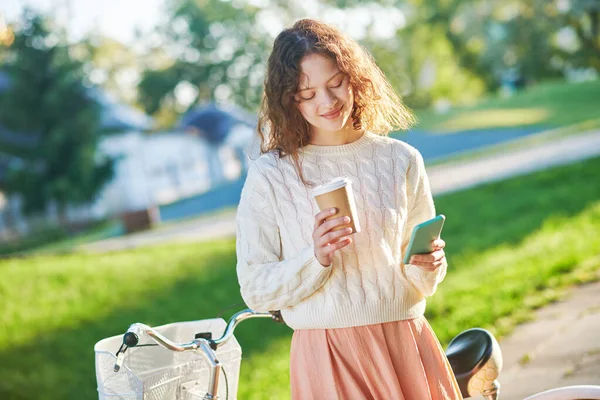 Девушка с чашкой кофе читает мессаж в мессенджере — стоковое фото