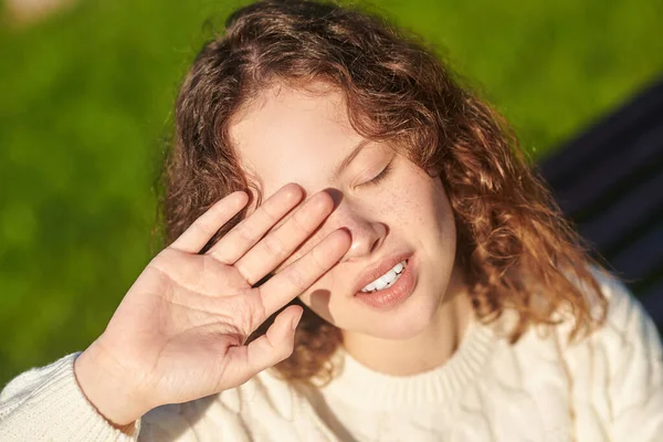 Una chica pelirroja cerrando los ojos del sol —  Fotos de Stock