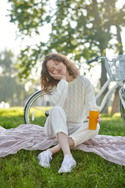 Una chica de blanco sentada sobre una hierba en el parque —  Fotos de Stock