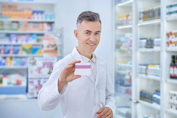 Человек в белом халате показывает лекарственное средство — стоковое фото