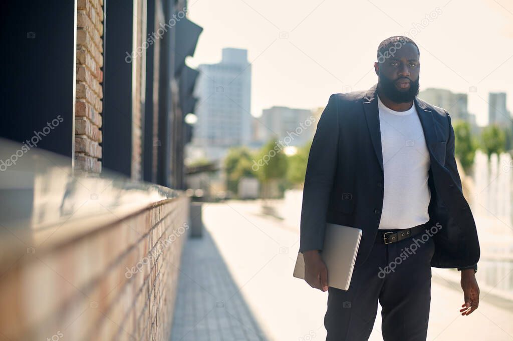 A dark-skinned man in an elegant suit in the street