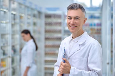 Arkasında dosyasıyla gülümseyen eczacı ve kadın