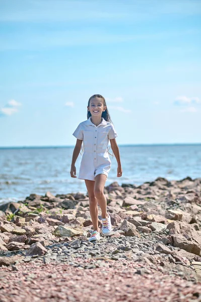 Plajda yürüyen beyaz elbiseli bir kız.