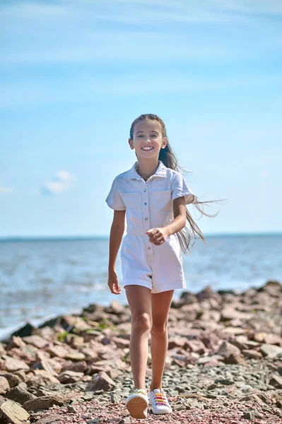 Plajda yürüyen beyaz elbiseli bir kız.