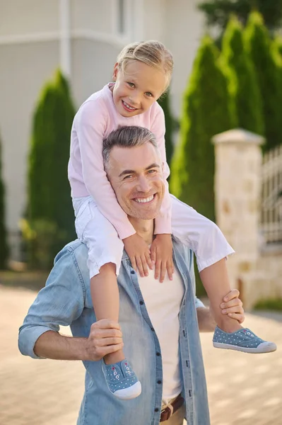 Little girl sitting on daddys shoulders — Stock Photo, Image