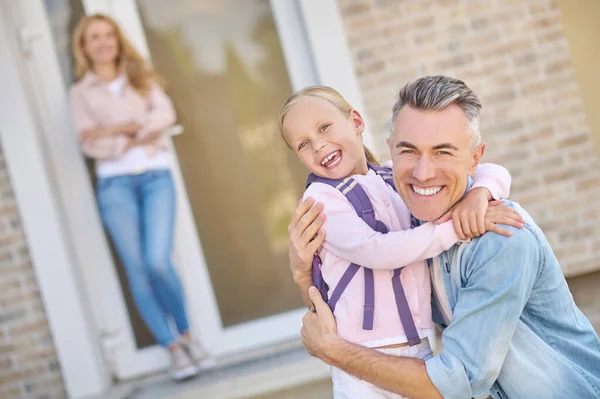 Joyful dad and daughter hugging near house