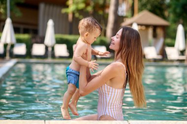Yüzme havuzunda çocuğuyla güzel bir genç kadın.