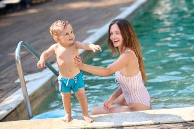 Yüzme havuzunda çocuğuyla güzel bir genç kadın.