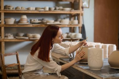 Saksıyı boyarken olaya karışan sevimli bir kadın çömlekçi.