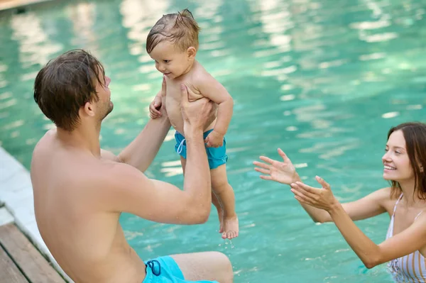 Uma jovem família passando tempo em uma piscina de verão — Fotografia de Stock